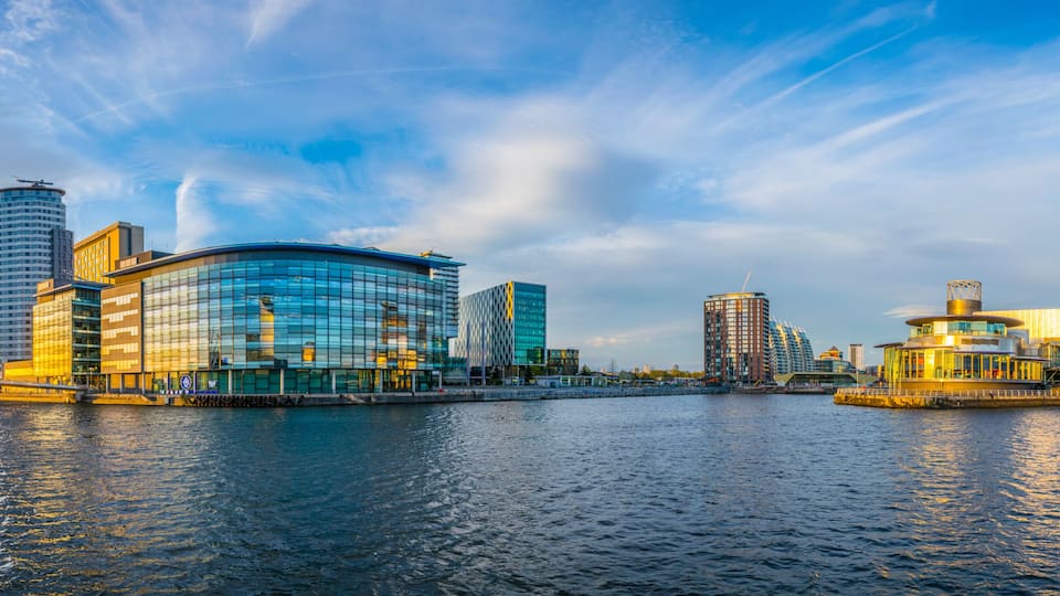 A waterfront cityscape with modern architecture, a bridge, and a river.