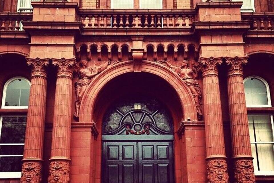 A red brick building with ornate columns and a large arched entrance.