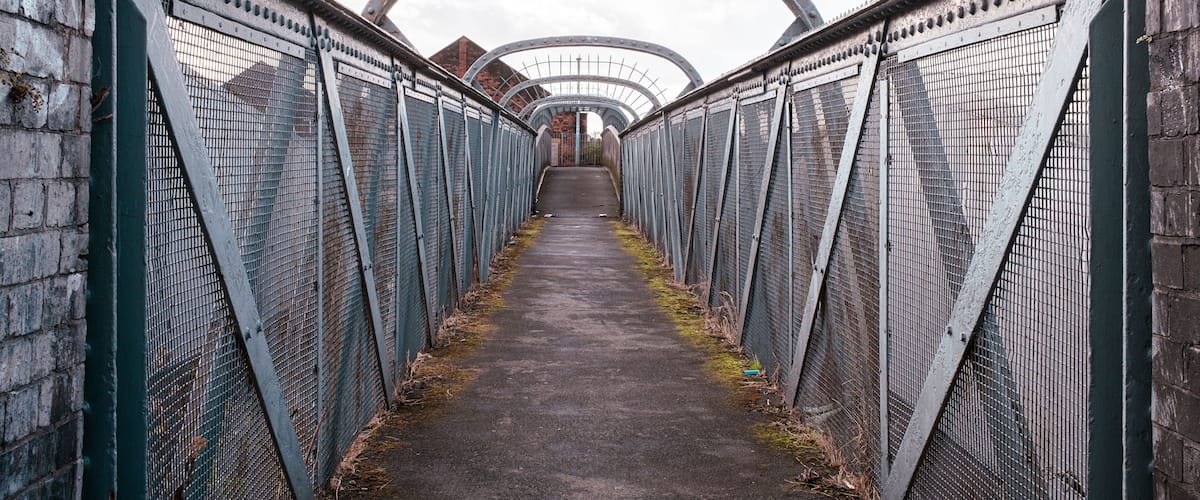 A pedestrian bridge with metal railings and a concrete path.