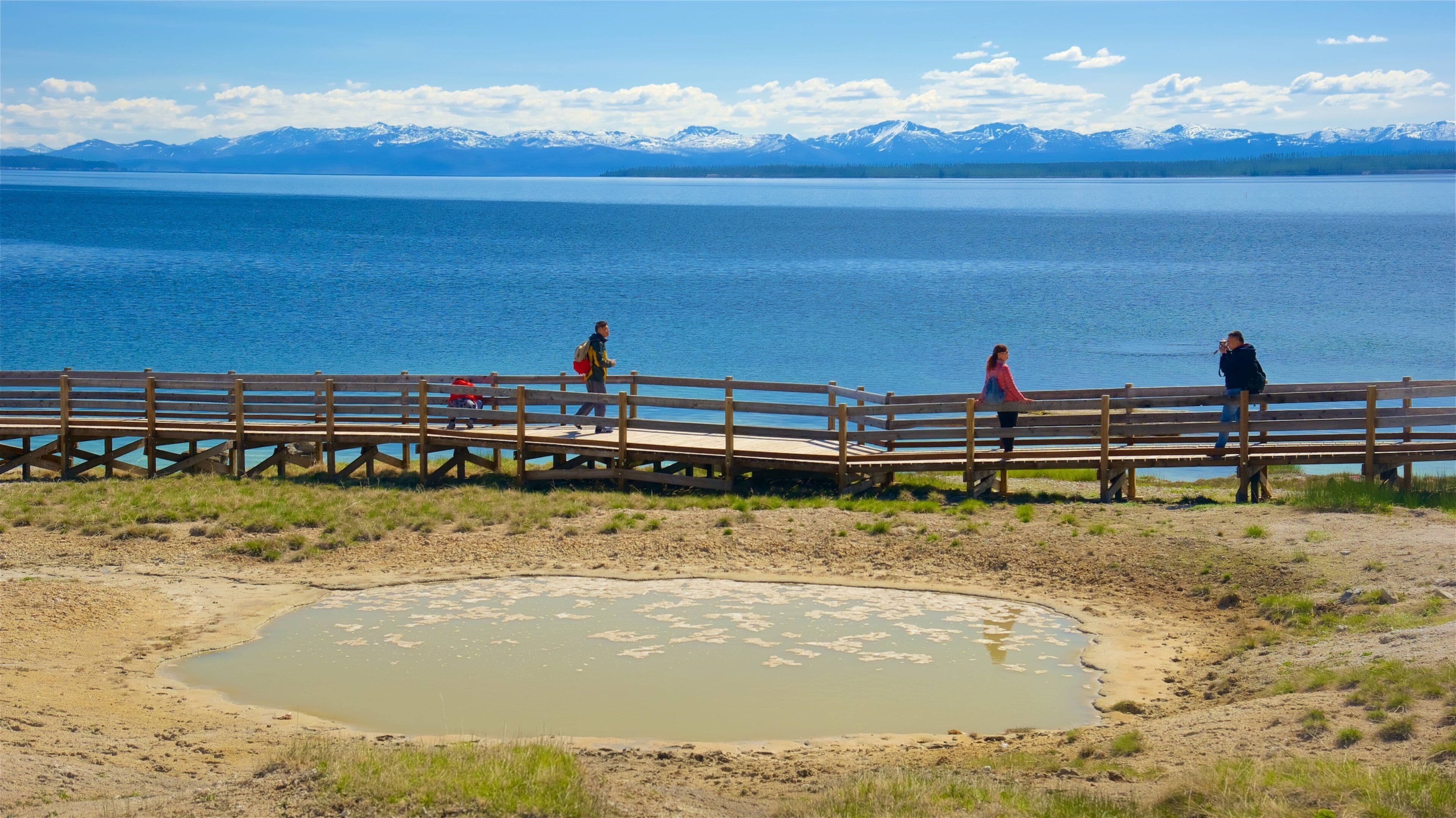 A wooden pier extending over a lake with mountains in the background.
