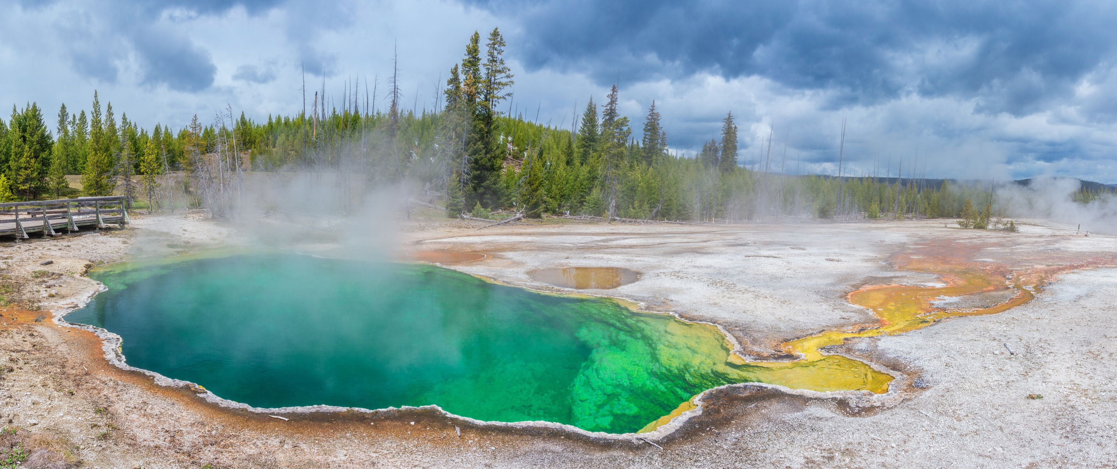 A geothermal area with mineral deposits and a wooden viewing platform.