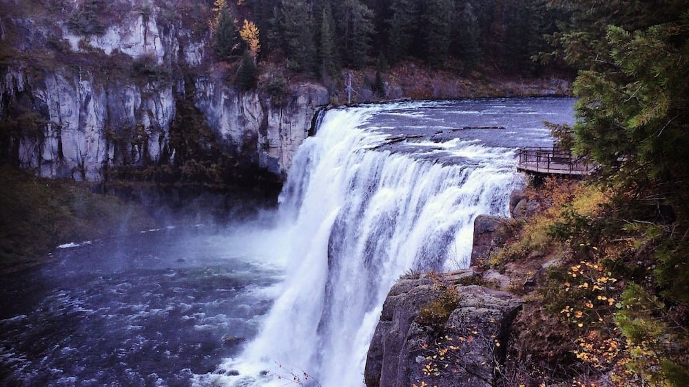 A waterfall cascading over a rocky cliff surrounded by dense forest.