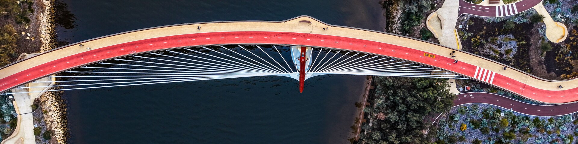 Ponte suspensa sobre um rio, com vegetação e estradas ao redor.