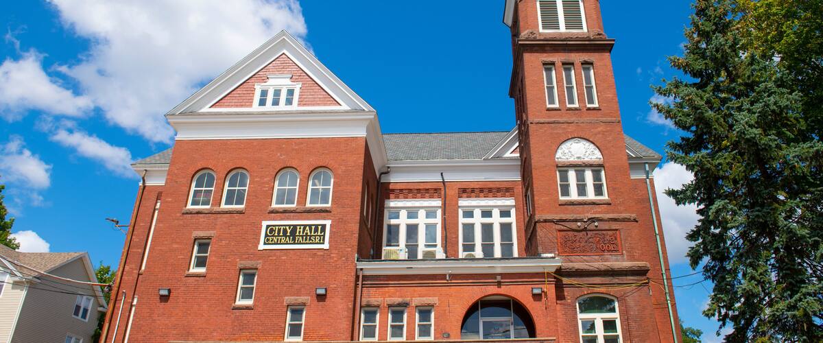 A red brick building with a clock tower and a sign reading "City Hall Central Falls."