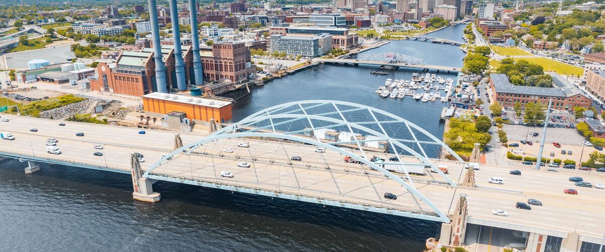 A cityscape with a large bridge, a river, and several industrial buildings.