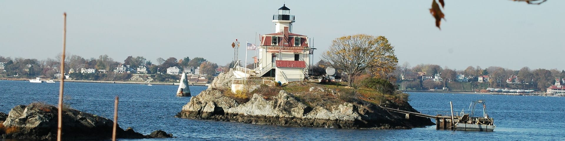 A lighthouse on a rocky island with a clear blue sky and calm water.