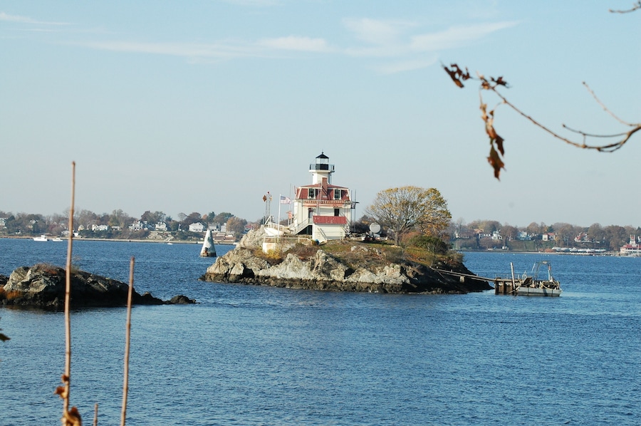 A lighthouse on a rocky island with a clear blue sky and calm water.