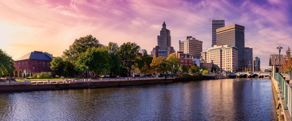 A river with a bridge, a city skyline, and trees.