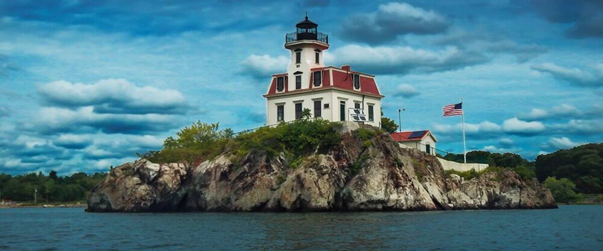 Un phare sur une île rocheuse, avec un drapeau américain.