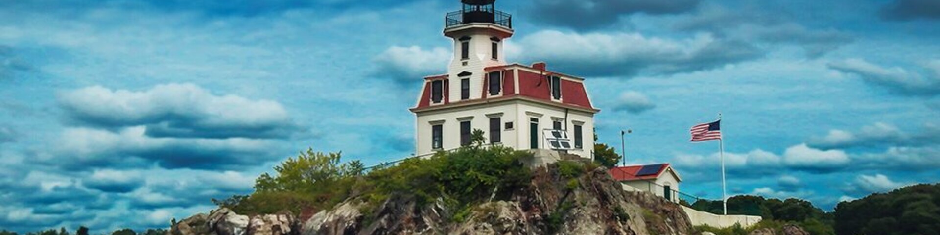 Un faro en una isla rocosa con una bandera estadounidense.