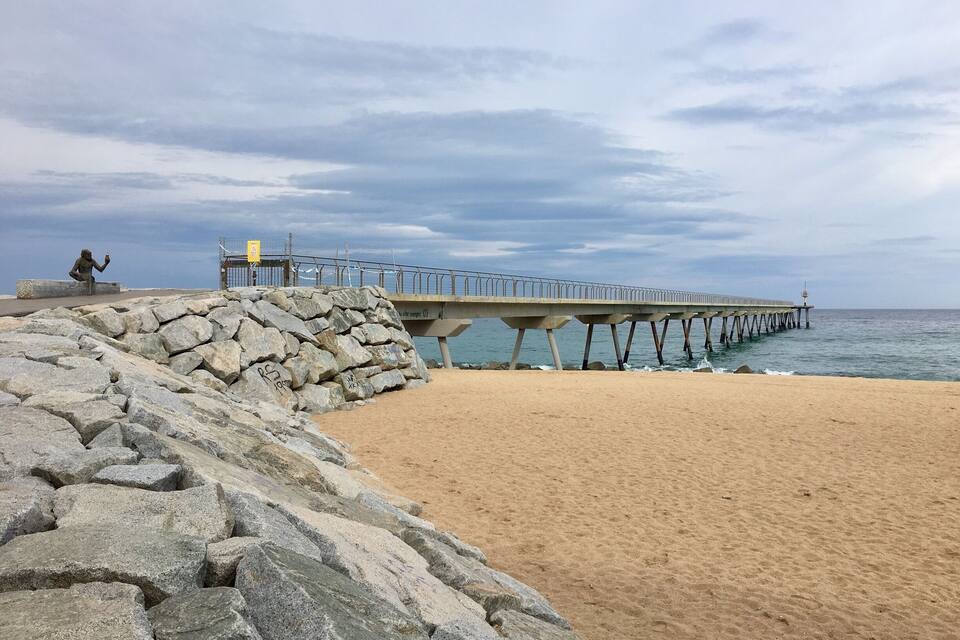 A rocky beach with a pier extending into the sea.