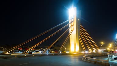 Vista nocturna de un puente atirantado con cables iluminados y una torre central.