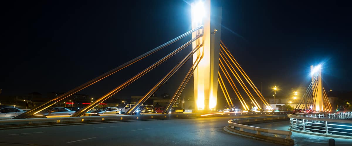 A nighttime view of a cable-stayed bridge with illuminated cables and a central tower.