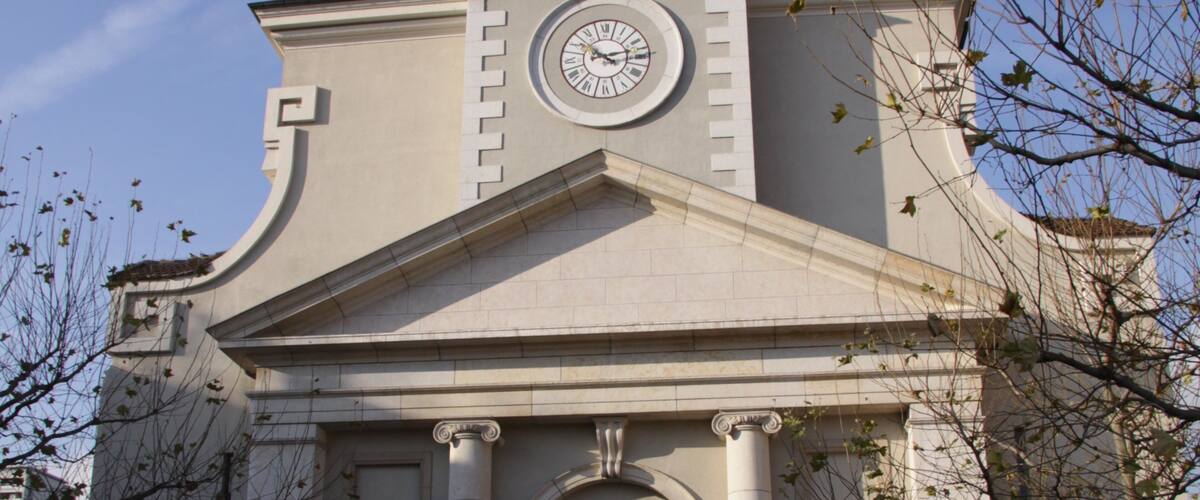A building with a clock tower, columns, and a triangular pediment.