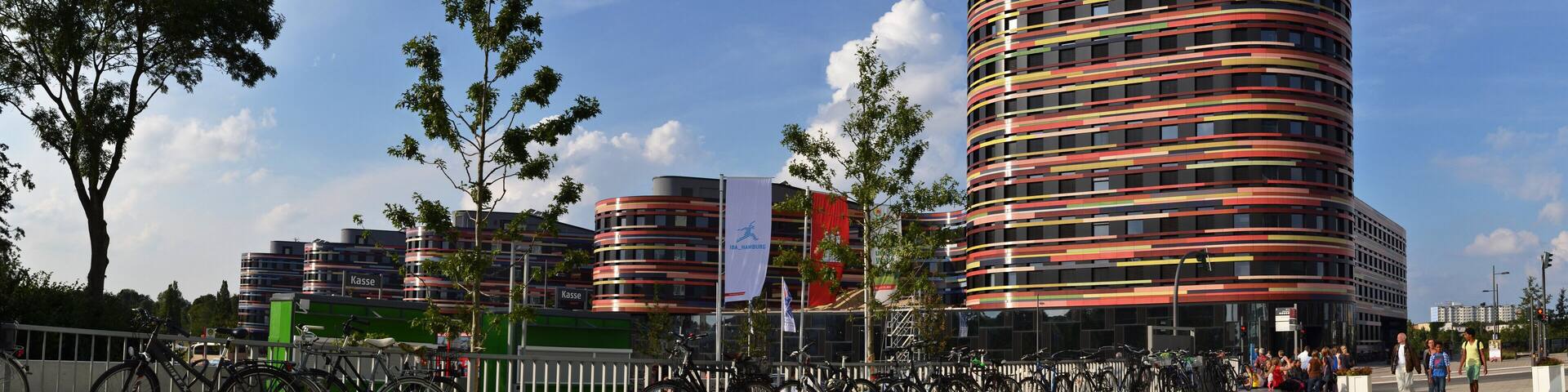A modern, curved building with horizontal stripes in red, yellow, and black.