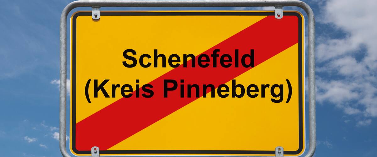 A road sign with the text "Schenefeld (Kreis Pinneberg)" against a blue sky with clouds.