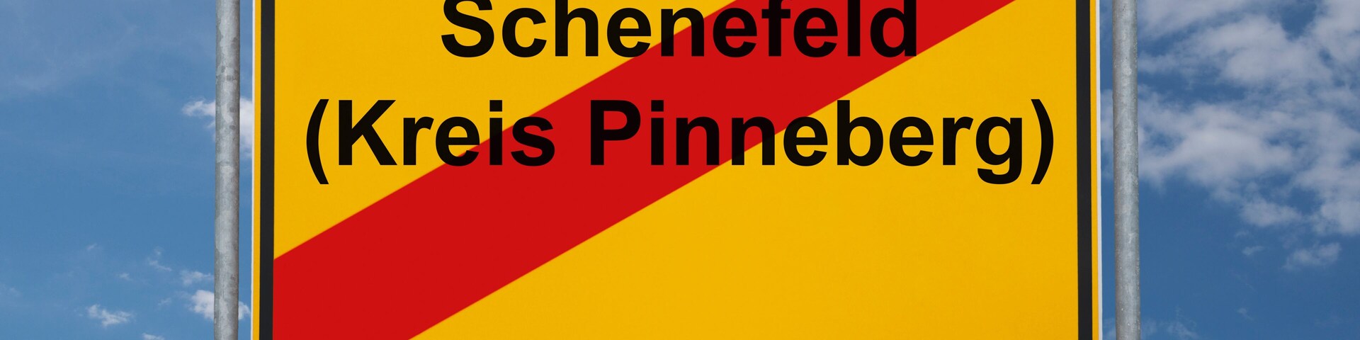 A road sign with the text "Schenefeld (Kreis Pinneberg)" against a blue sky with clouds.