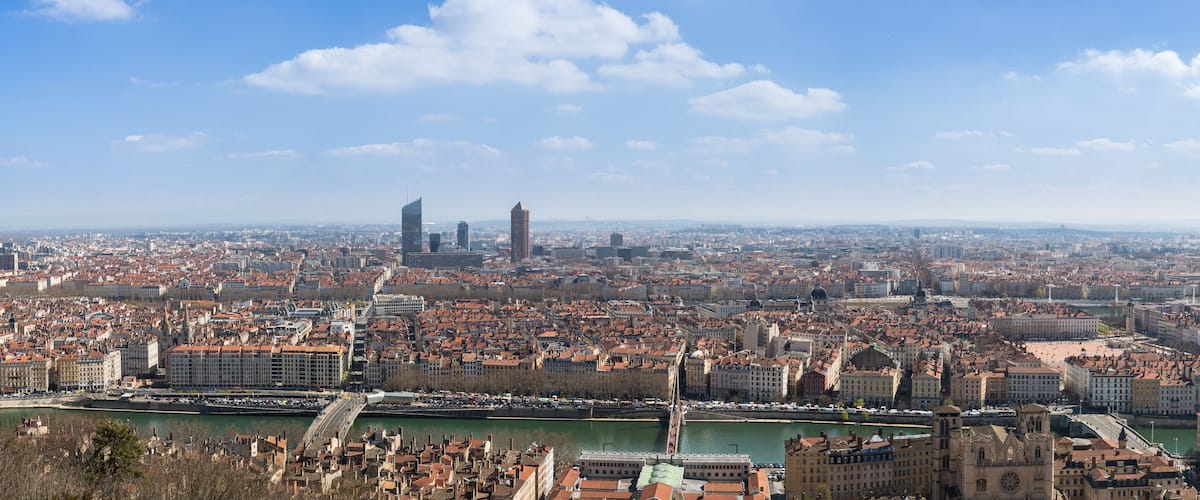 A panoramic view of a city with a river, historic buildings, and modern skyscrapers.