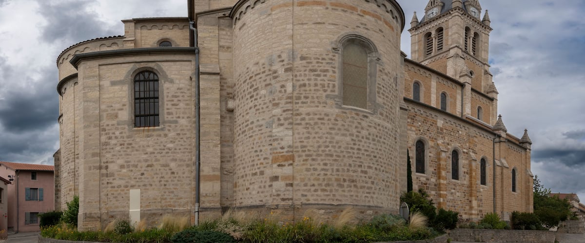 A historic stone church with a bell tower and a round tower.