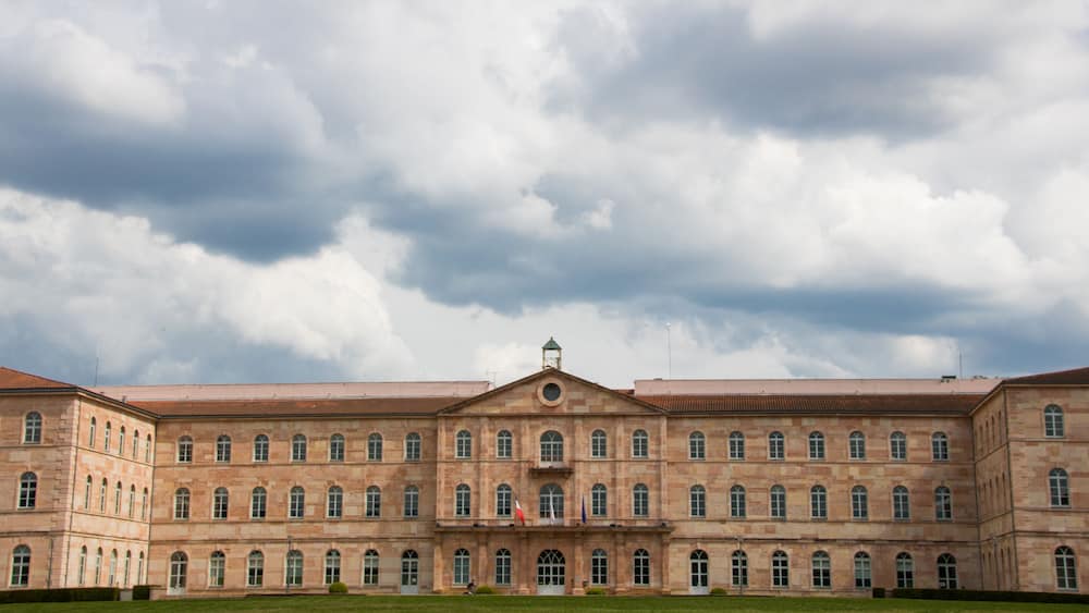 A large, historic building with a symmetrical facade, arched windows, and a central entrance.