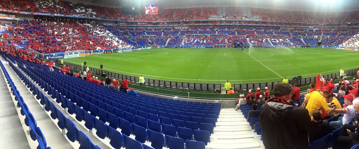 A large stadium with blue seats and a green field.