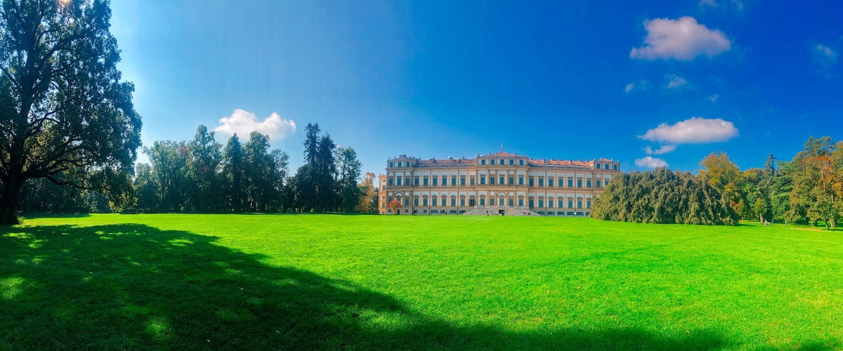 A large green lawn, a historic building, and a clear blue sky.