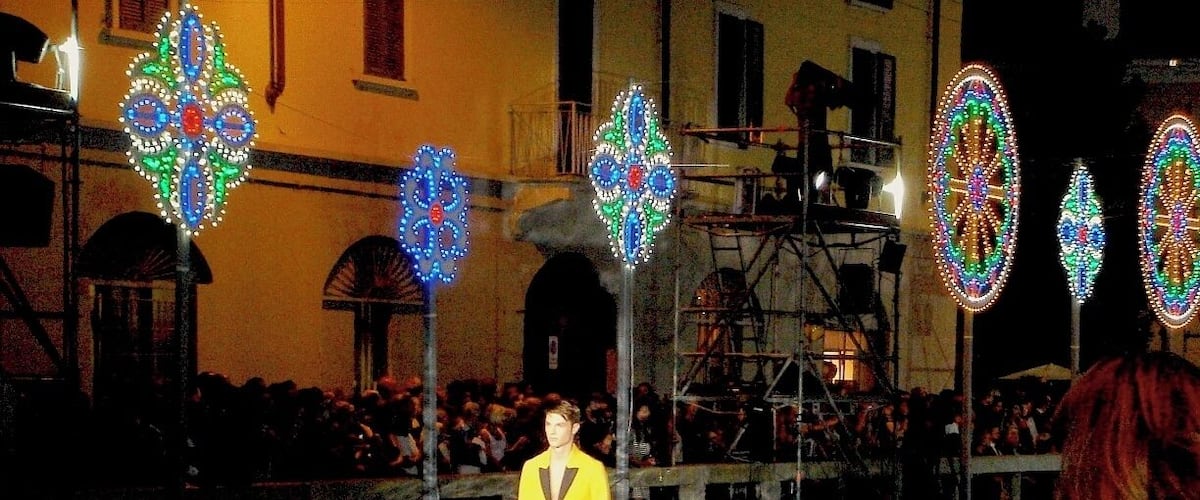 A person walking on a runway with colorful, illuminated decorations in the background.