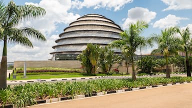 Un moderno edificio de diseño arquitectónico circular, rodeado por un jardín bien cuidado con palmeras y otra vegetación.