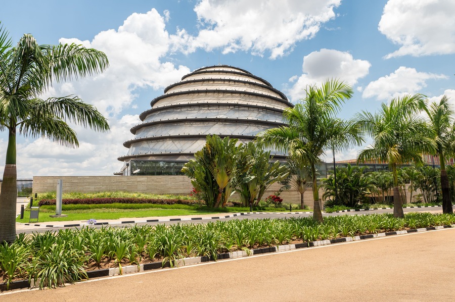 Un moderno edificio de diseño arquitectónico circular, rodeado por un jardín bien cuidado con palmeras y otra vegetación.