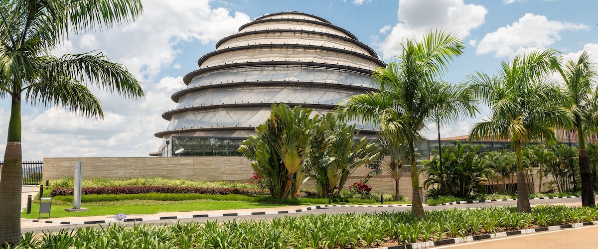 A modern architectural building with a circular design, surrounded by a well-maintained garden with palm trees and other greenery.