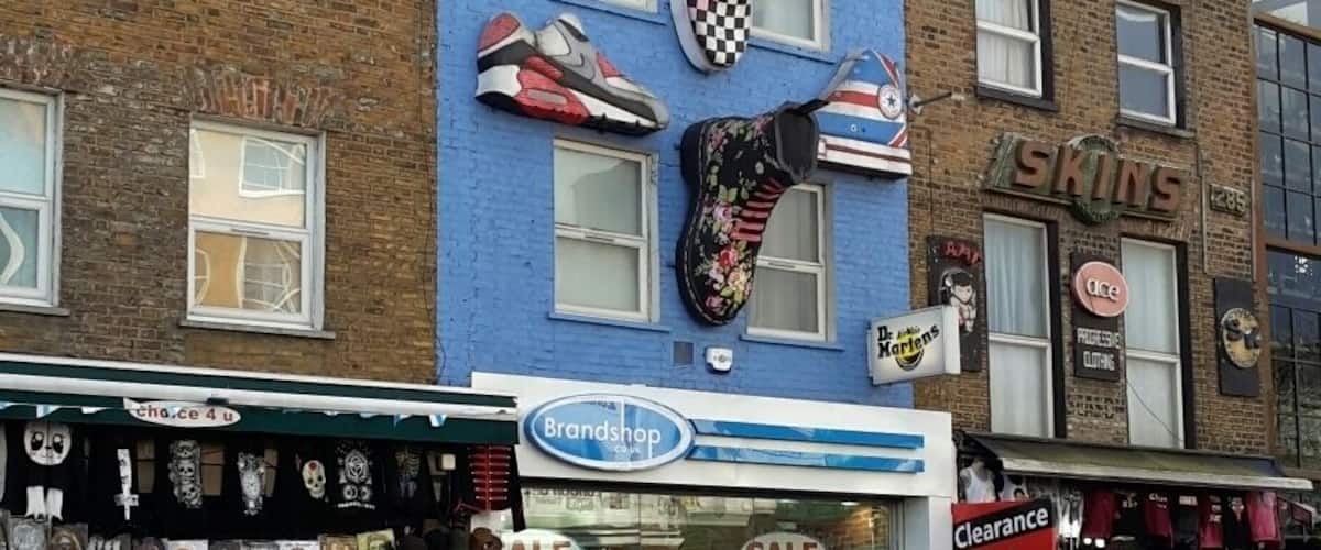 A street with shops, including a shoe store with a blue facade and a sign for 'Brandshop'.