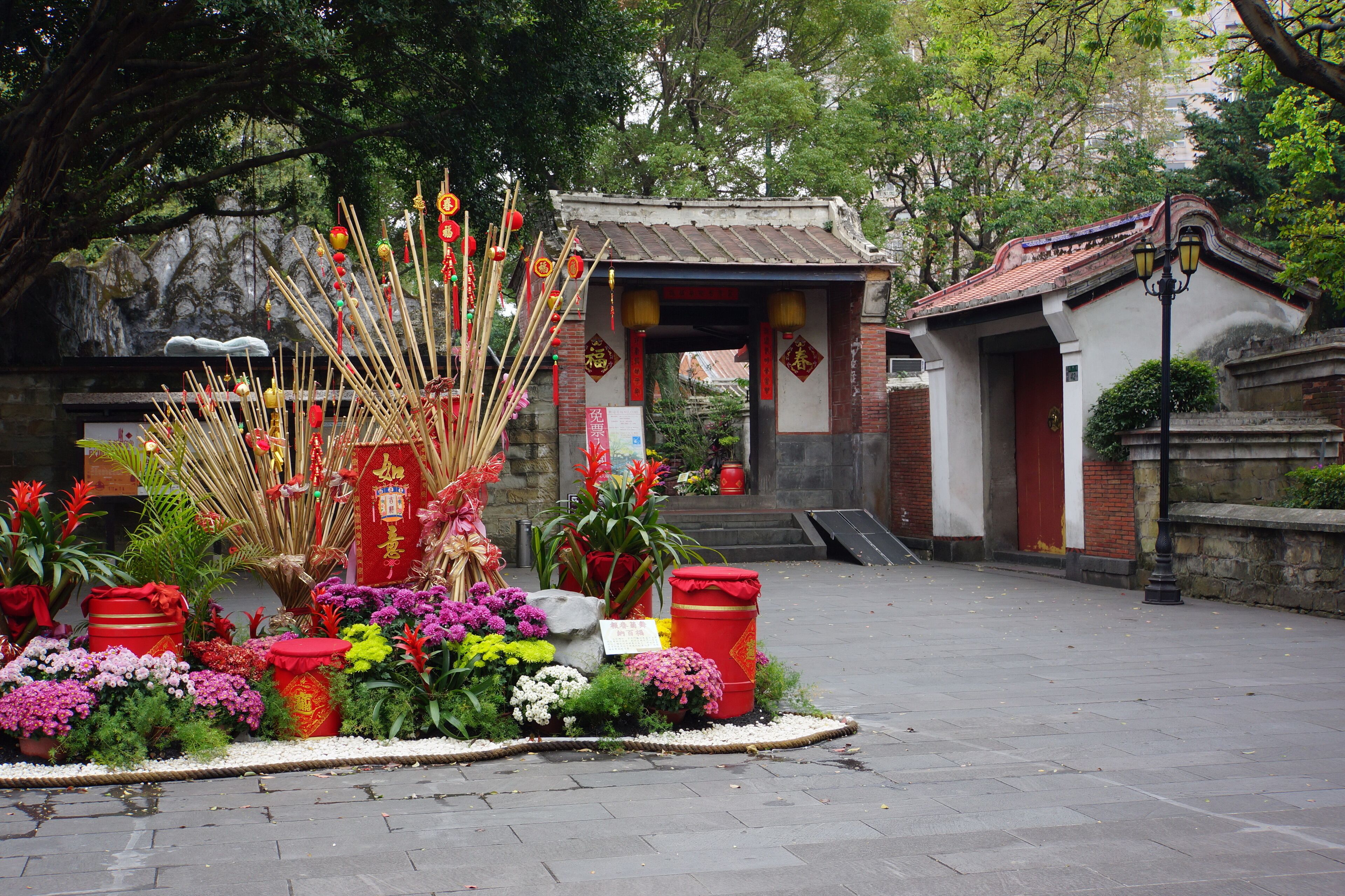 Ein traditioneller chinesischer Tempel mit roten Laternen, Räucherstäbchen und bunten Blumen.
