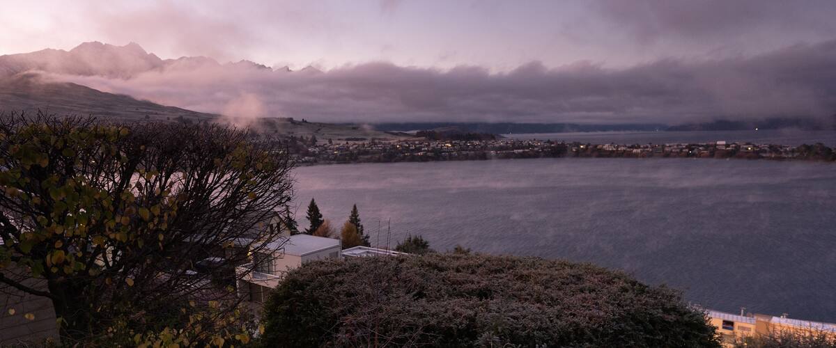 A coastal town with mountains in the background and a body of water in the foreground.