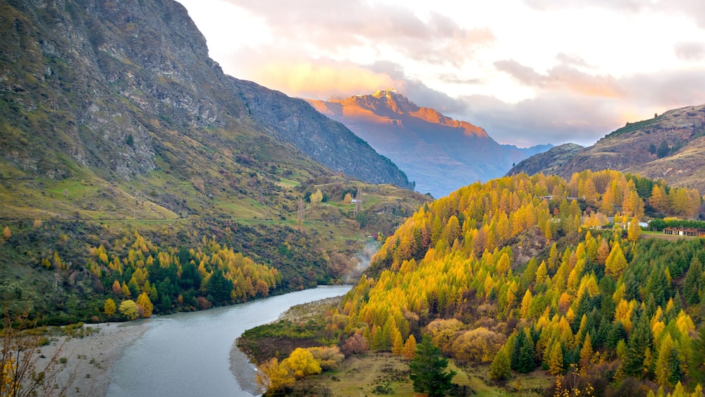 A river winding through a valley with autumn-colored trees and mountains in the background.
