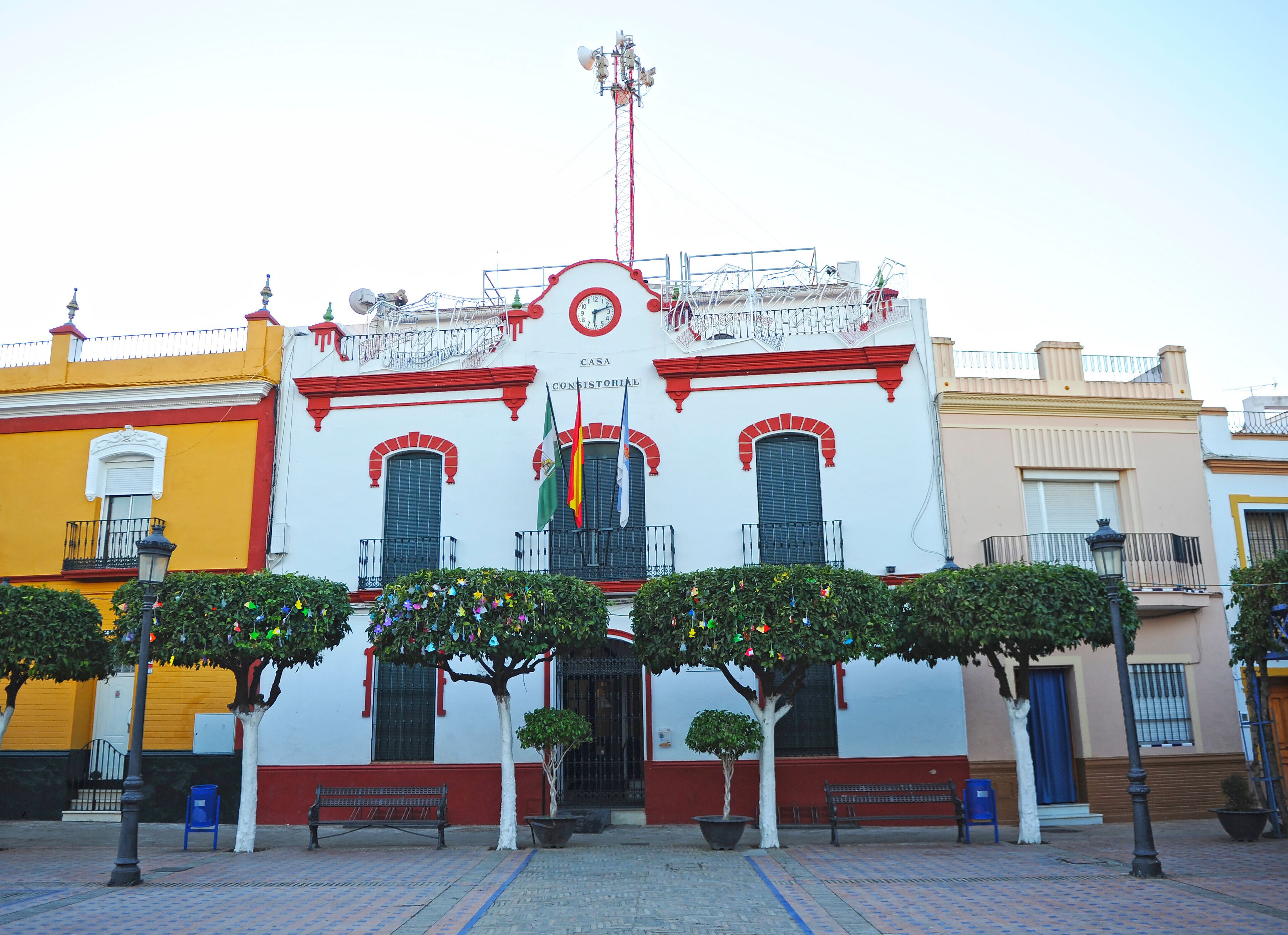 A historic building with red and white walls, a clock, and flags.