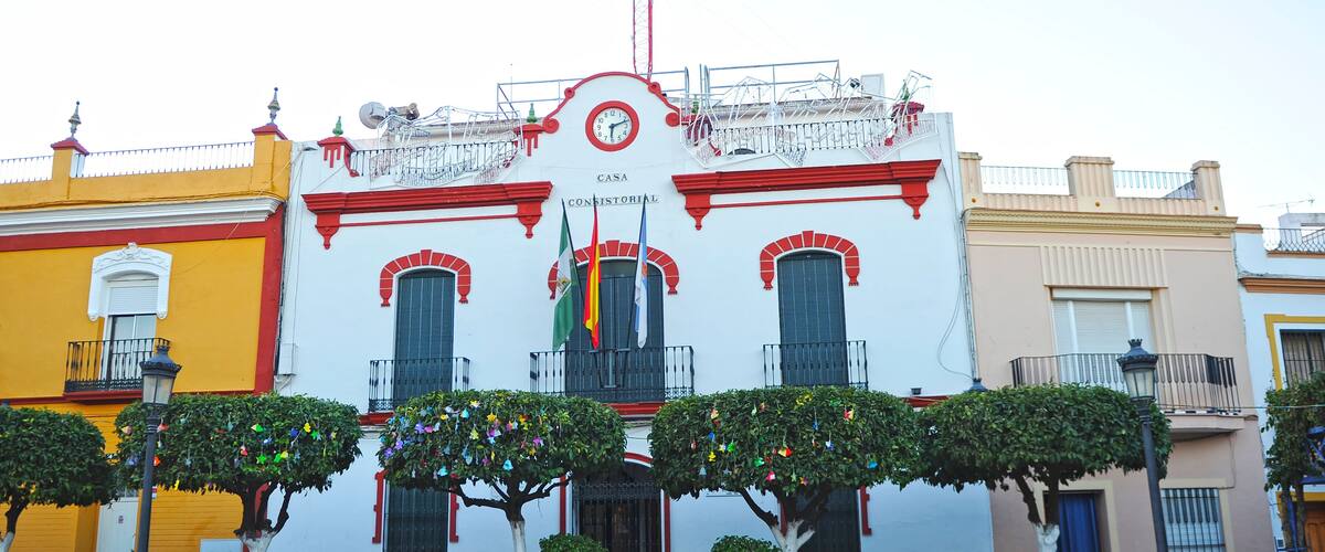 A historic building with red and white walls, a clock, and flags.