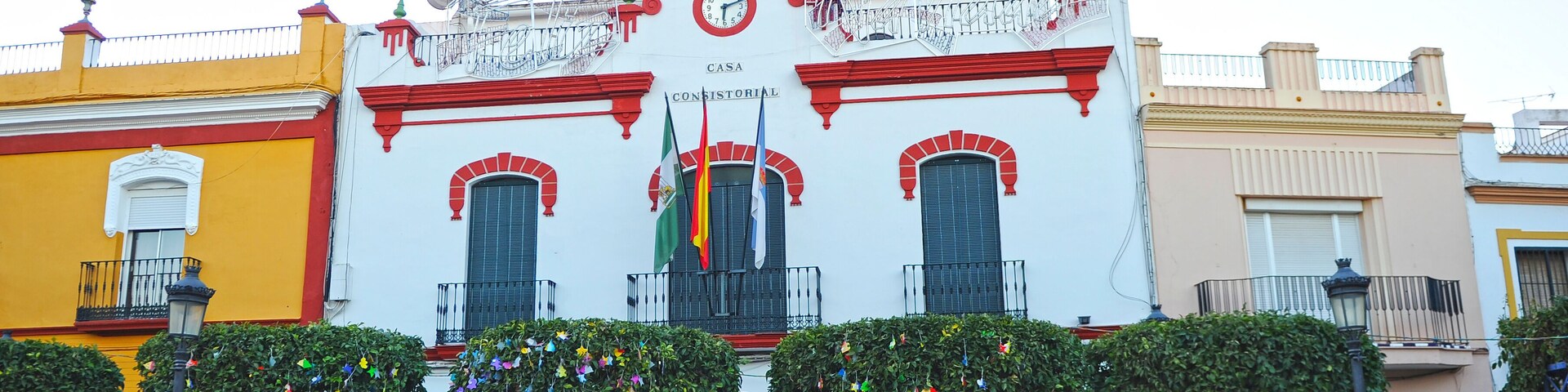 A historic building with red and white walls, a clock, and flags.