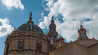 A historic building with a large dome and bell tower under a partly cloudy sky.