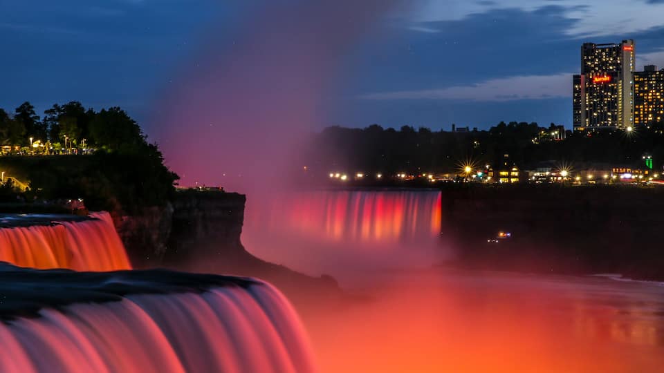 A waterfall with a cityscape in the background.