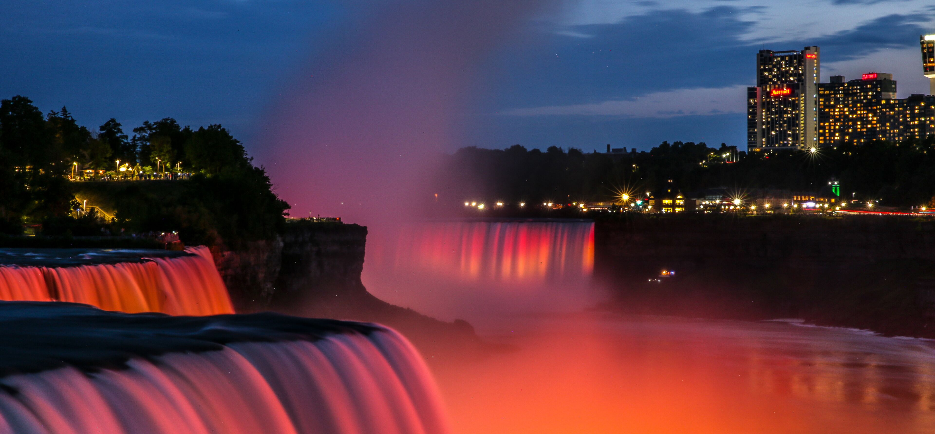 A waterfall with a cityscape in the background.