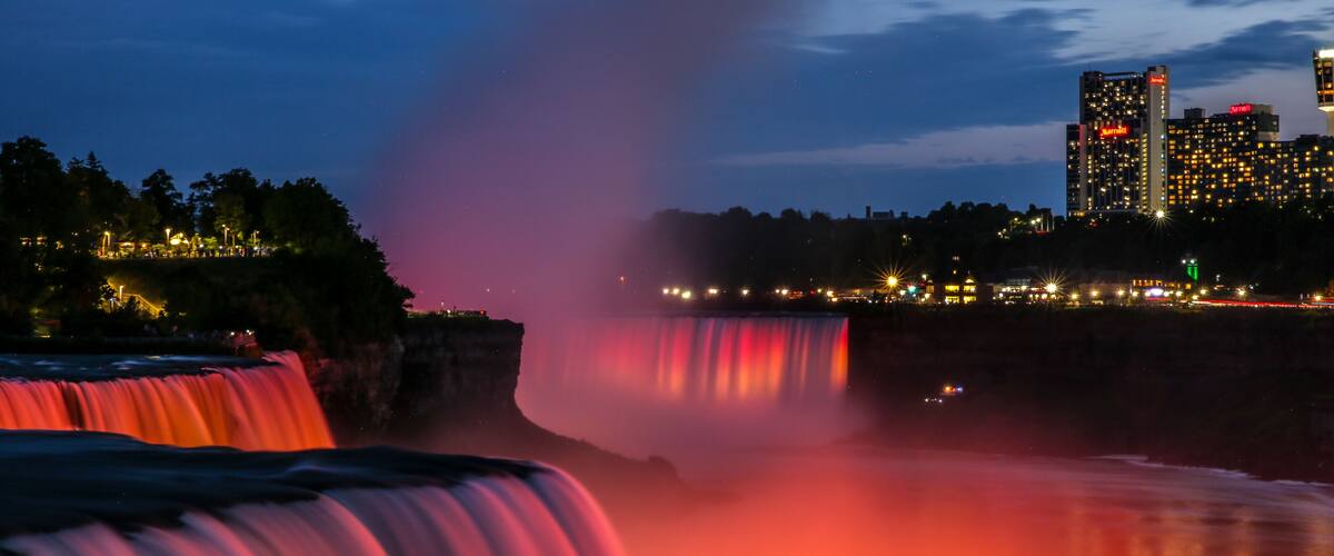 A waterfall with a cityscape in the background.