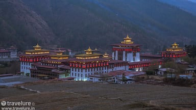 Un conjunto de edificios tradicionales tibetanos con techos dorados, al pie de montañas.
