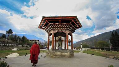 A traditional Tibetan structure with a red roof and intricate designs, surrounded by a stone base and a clear sky.