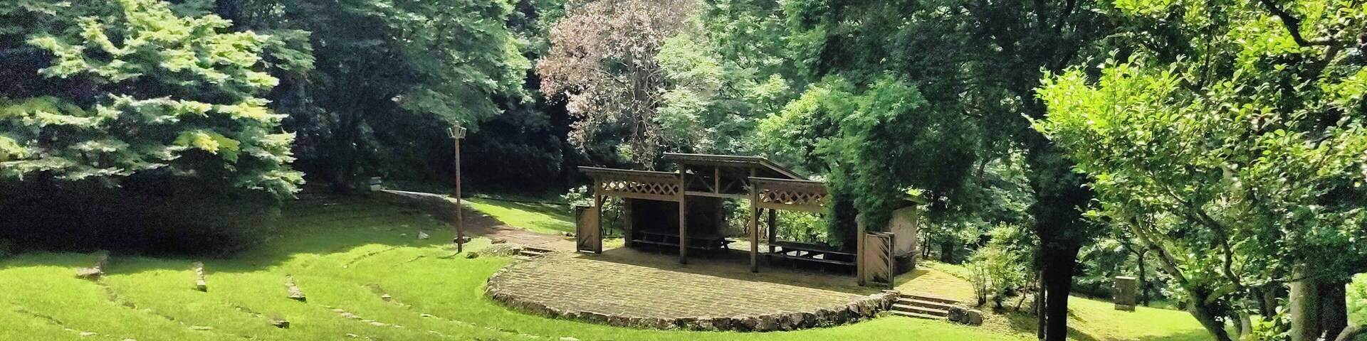 A park with a gazebo, green grass, and trees.