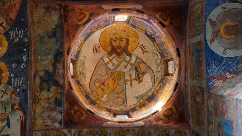 A detailed mosaic of a religious figure surrounded by smaller figures and symbols, set within a domed ceiling.