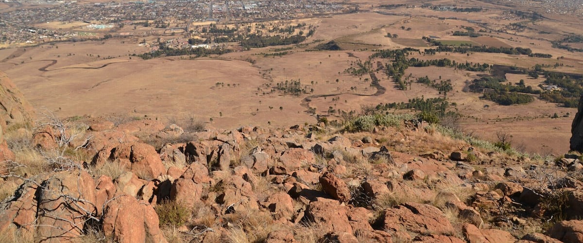 A vast desert landscape with rocky terrain and a distant town.