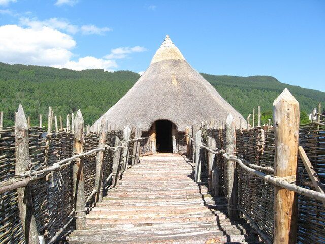 A thatched-roof structure with a wooden walkway leading to it.