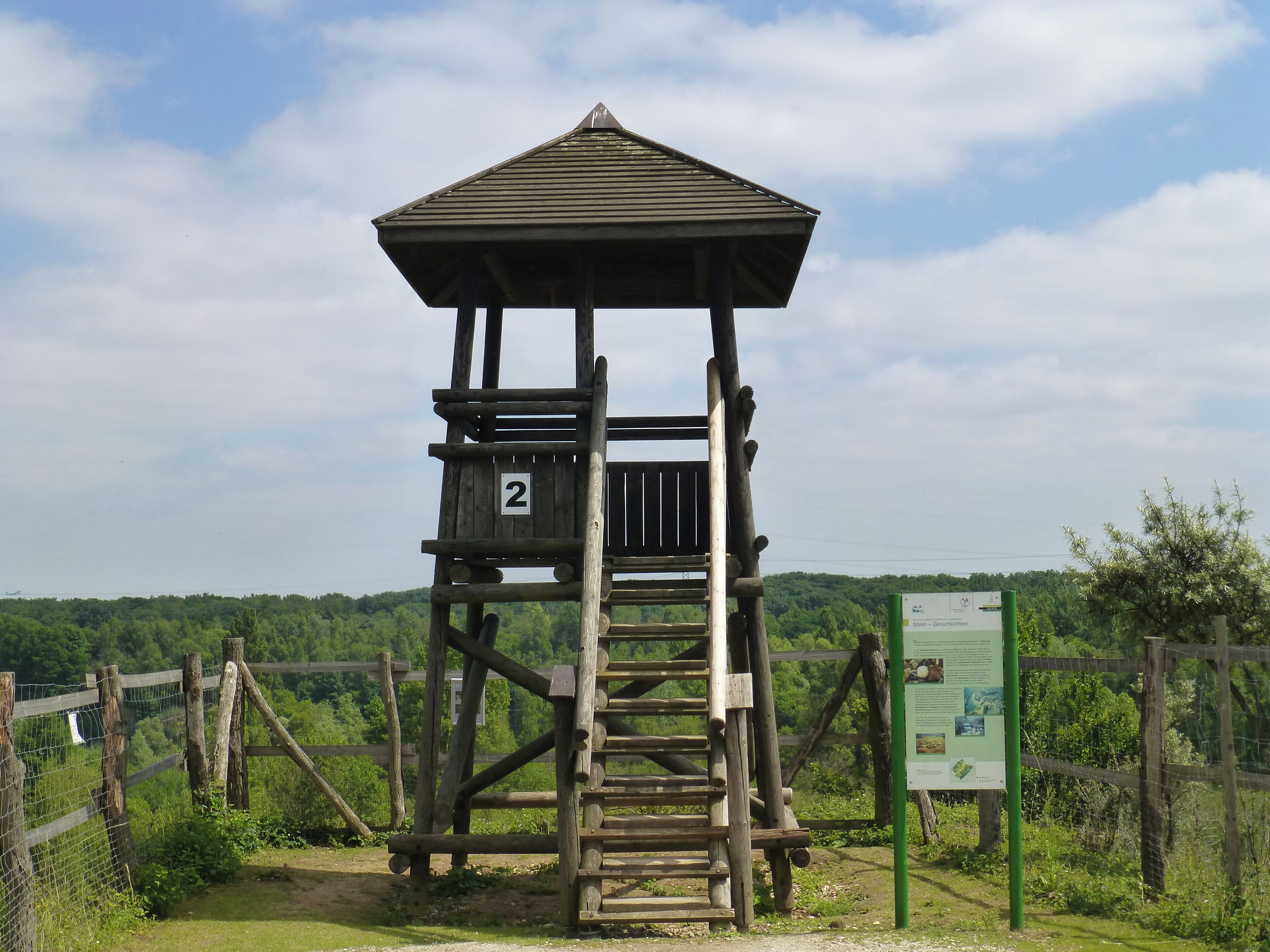 A wooden observation tower with a roof, labeled '2', surrounded by a fence and greenery.
