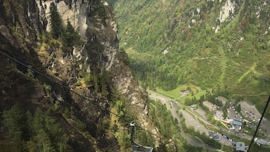 A cable car system in a mountainous area with steep cliffs and a valley below.