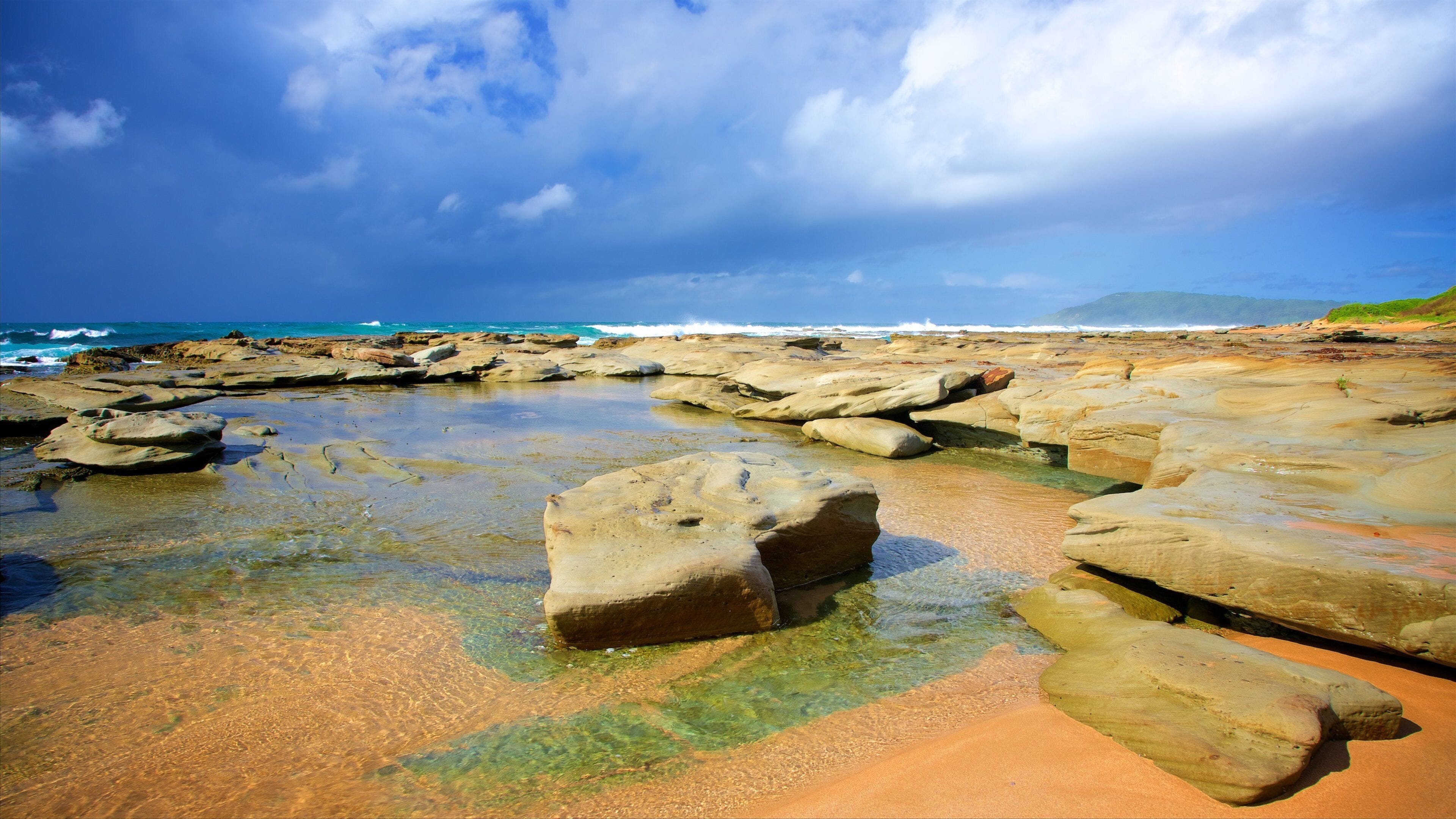 Una costa rocosa con agua cristalina y olas rompiendo contra las rocas.